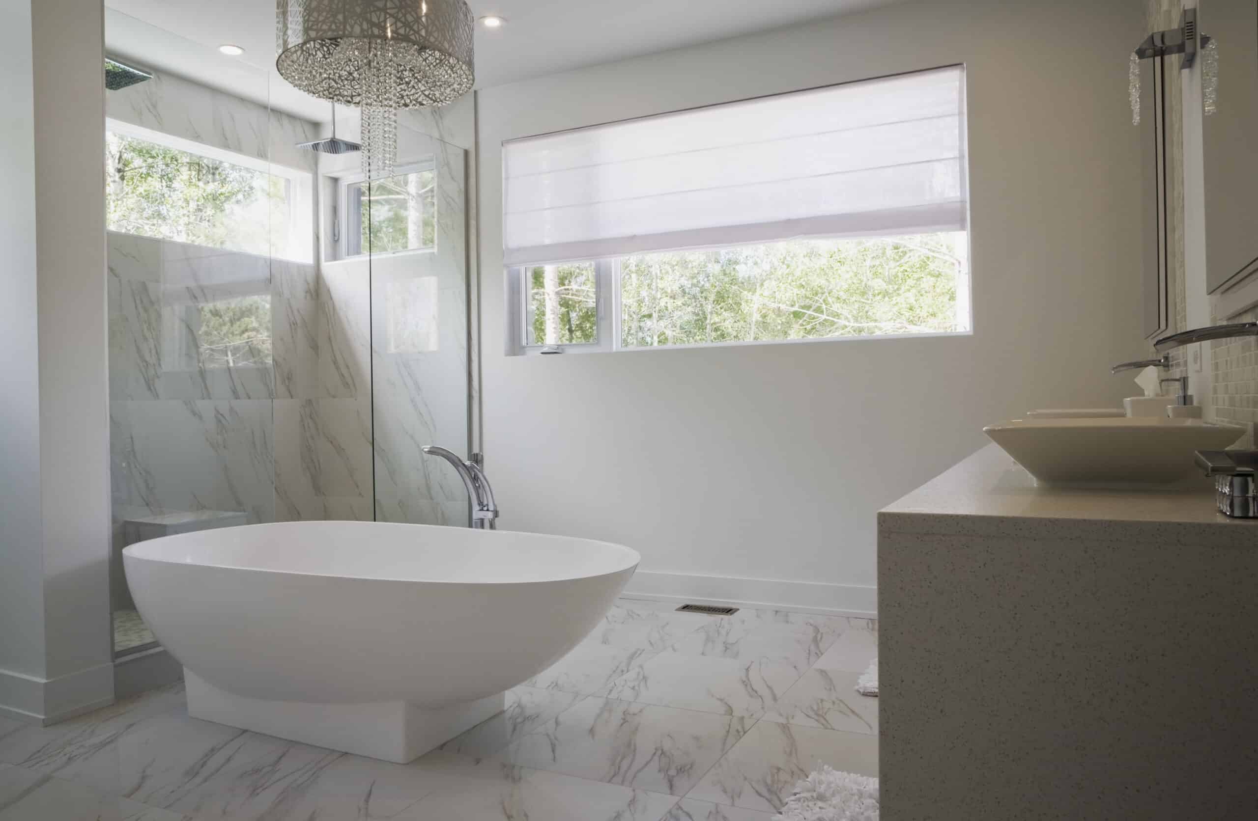 Modern bathroom with a freestanding tub, glass shower, and large window