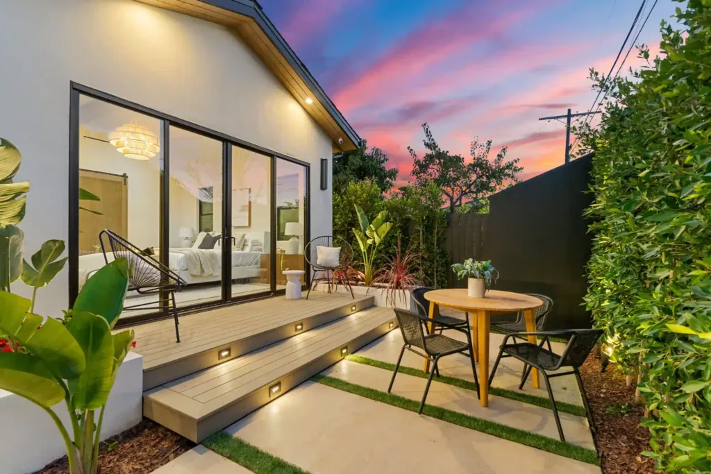 Modern backyard patio with outdoor seating and lush greenery at sunset