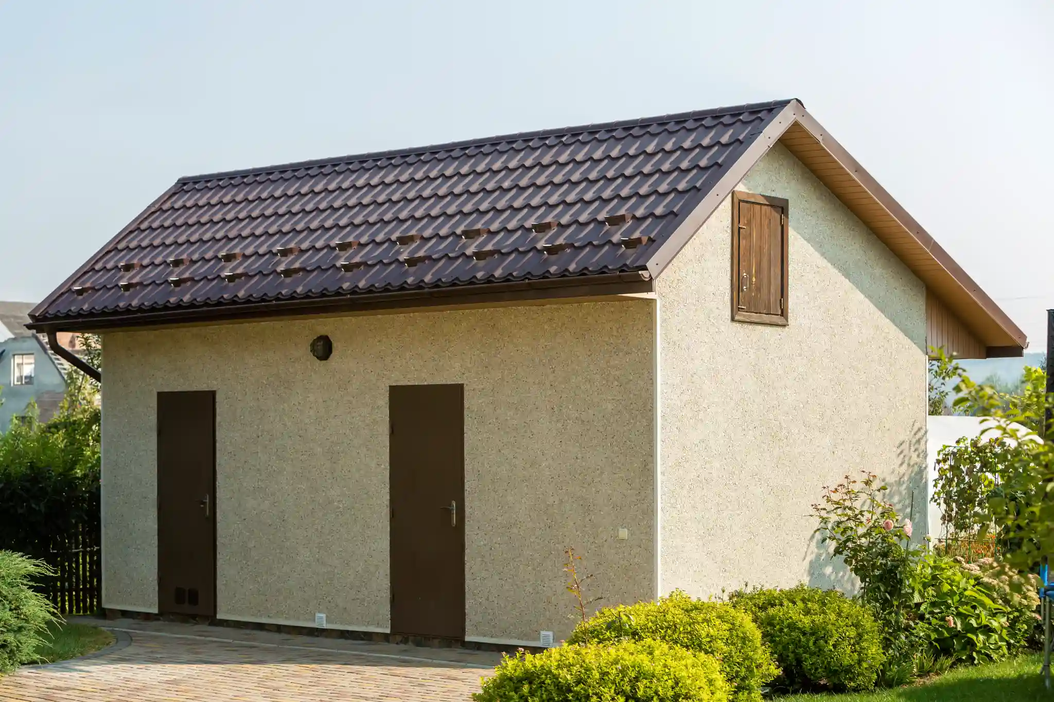 Small beige building with brown roof and two doors