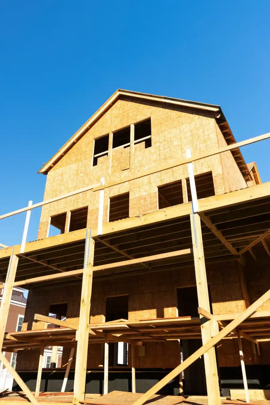 New wooden house frame under construction against a clear blue sky.
