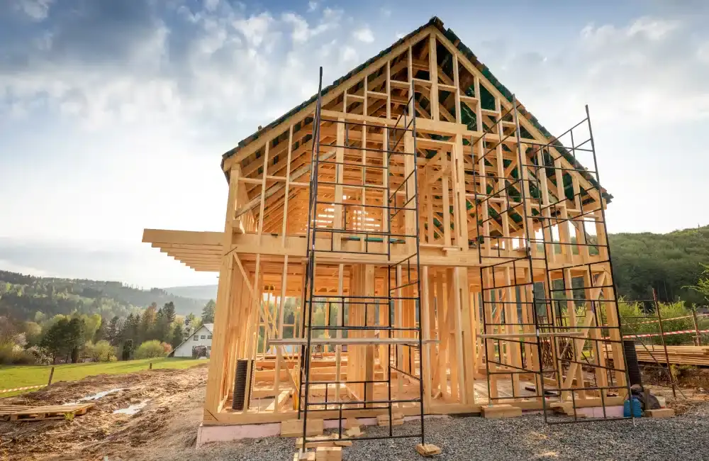 Wooden house frame under construction against a bright sky