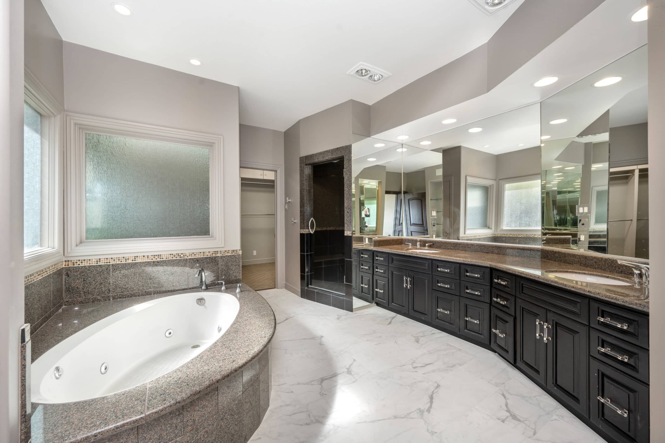 Luxury bathroom with large bathtub, dark wood vanity, and marble floor.