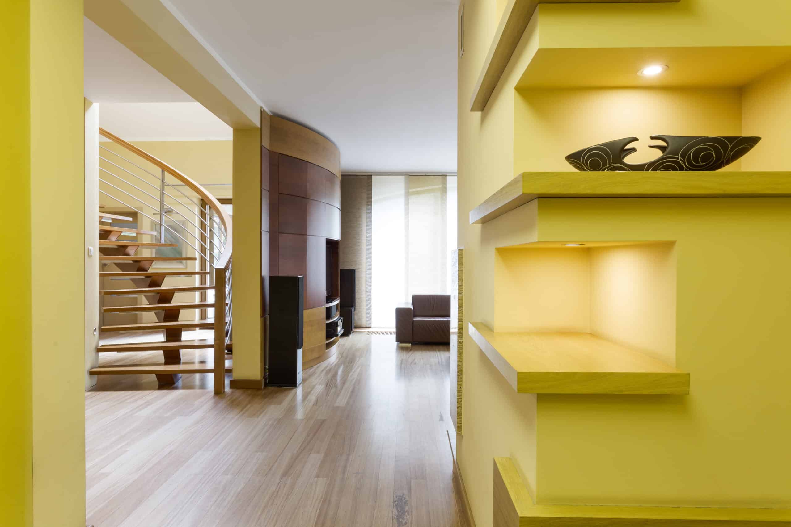 Modern living space with yellow walls, wooden floors, and a spiral staircase.
