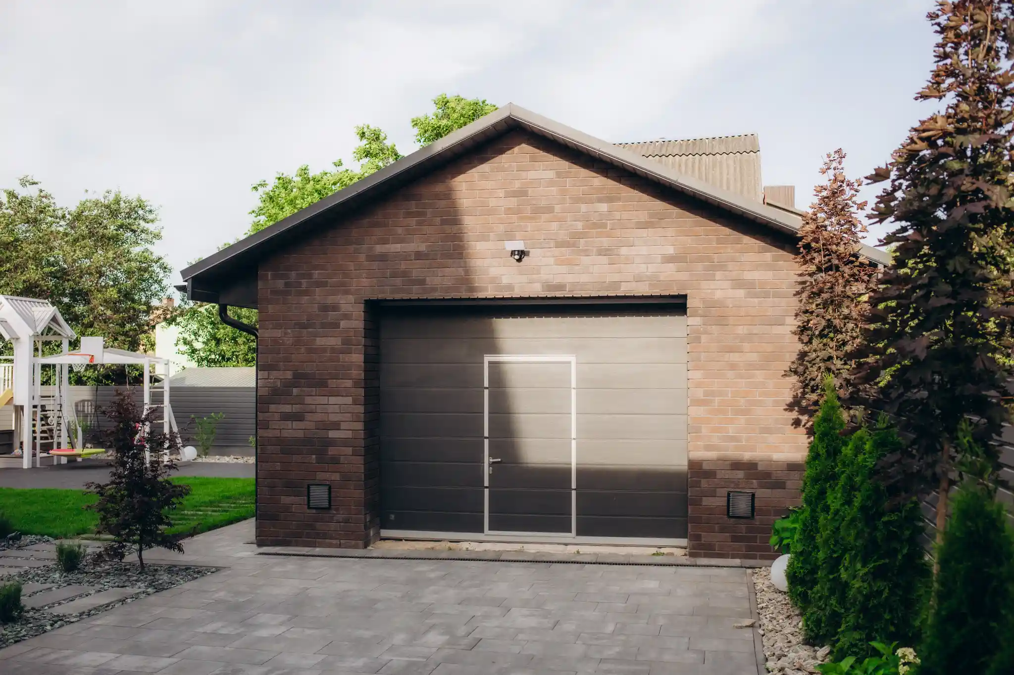 Brick garage with a dark gray door and a side entrance.