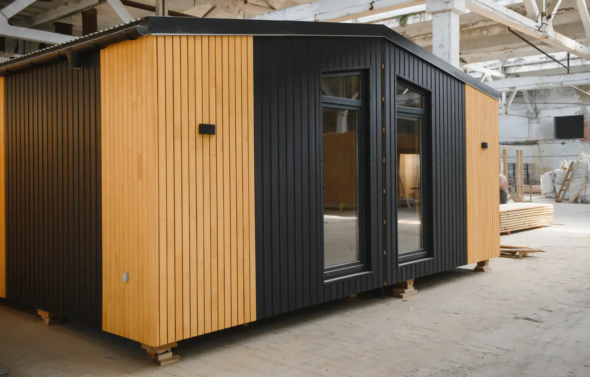 Modular house with black and light wood siding and two windows