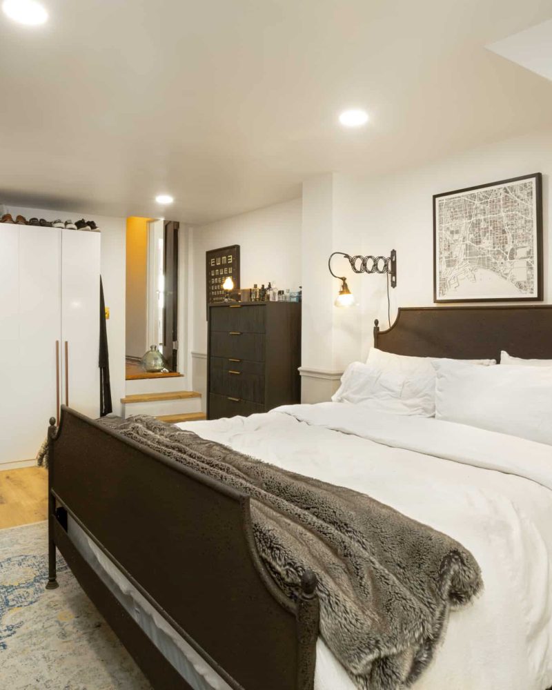 Bedroom with a bed, white wardrobes, and a chest of drawers.