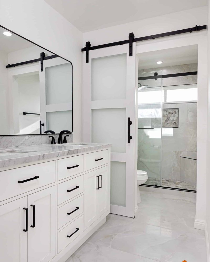 Modern bathroom with white vanity, marble countertop, and barn door shower.