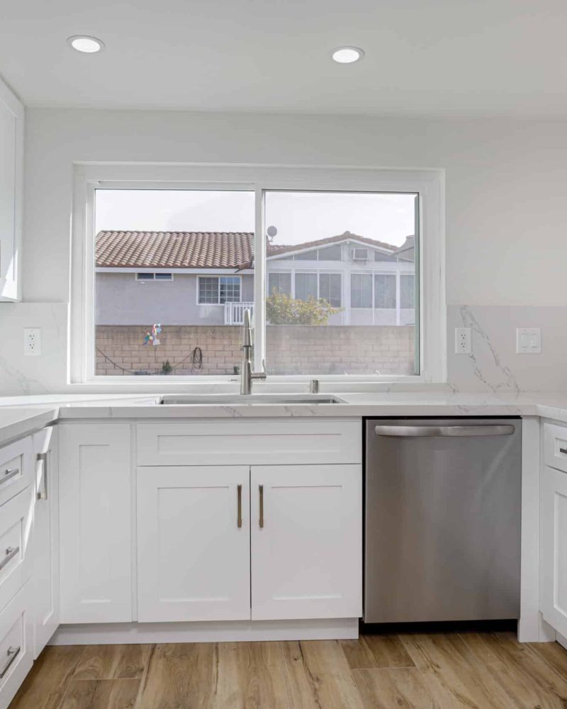 Modern white kitchen with stainless steel appliances and a window