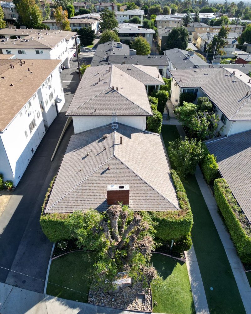 Aerial view of residential rooftops and green landscaping under clear sky