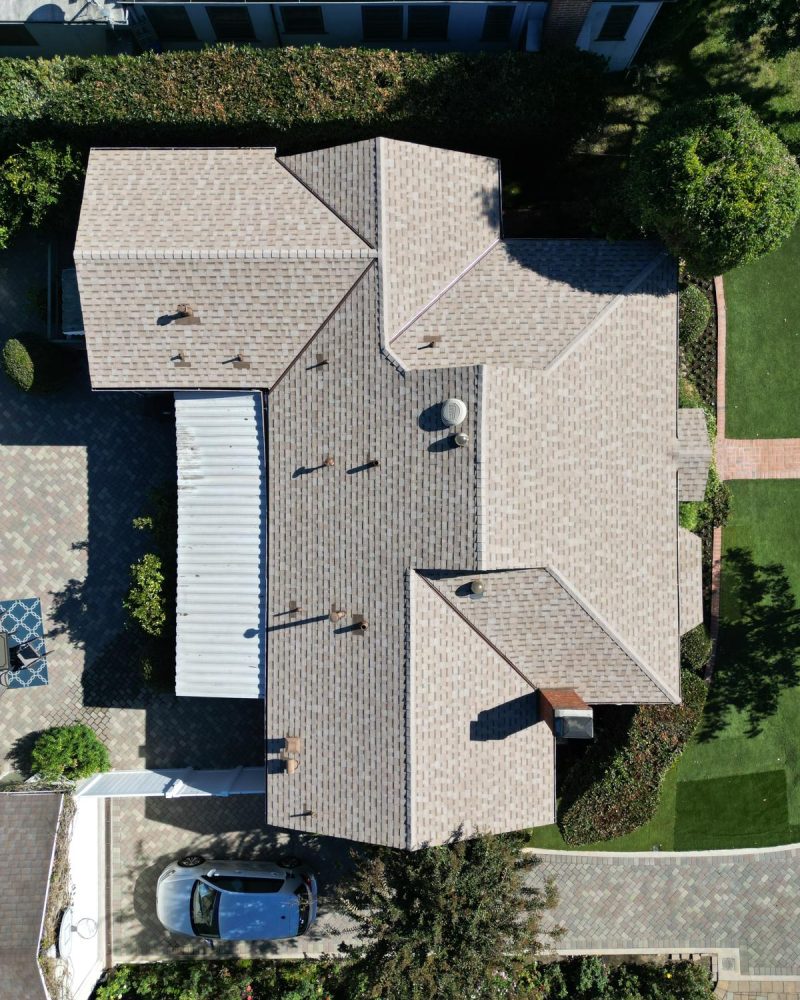 Aerial view of a house with a multi-gabled roof and surrounding greenery