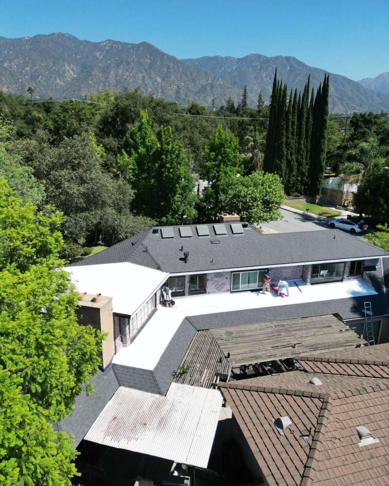 Aerial view of a house with a new white roof being installed
