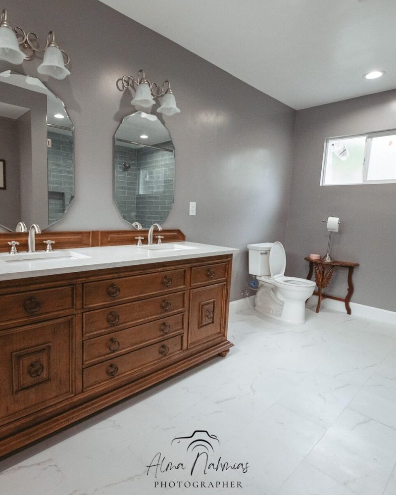 Bathroom with a wooden double vanity, two mirrors, and a toilet.
