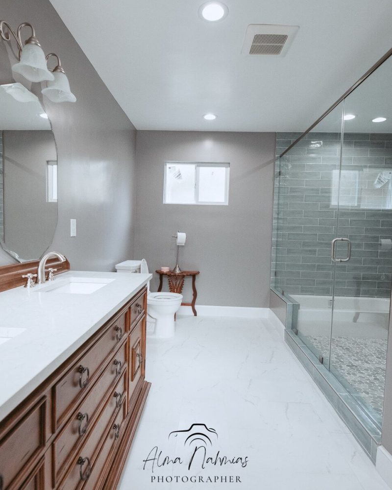 Modern bathroom with a double vanity, large mirror, toilet, and glass shower.