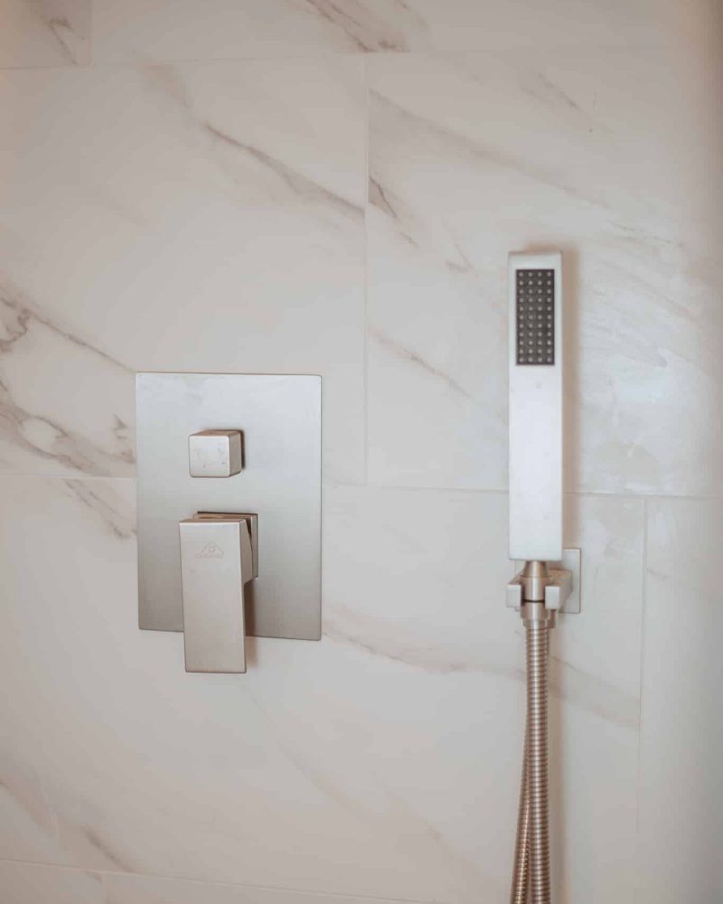 Modern shower with white marble tiles and brushed nickel fixtures
