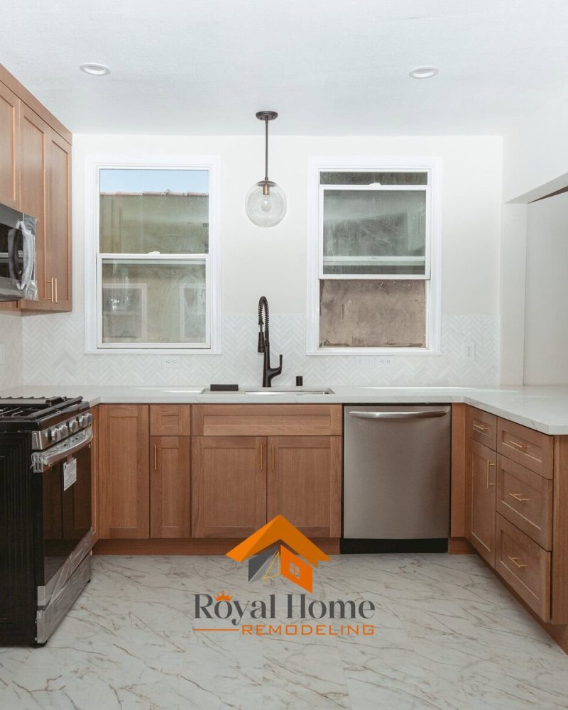 Modern kitchen with light wood cabinets, white countertops, and stainless steel appliances.