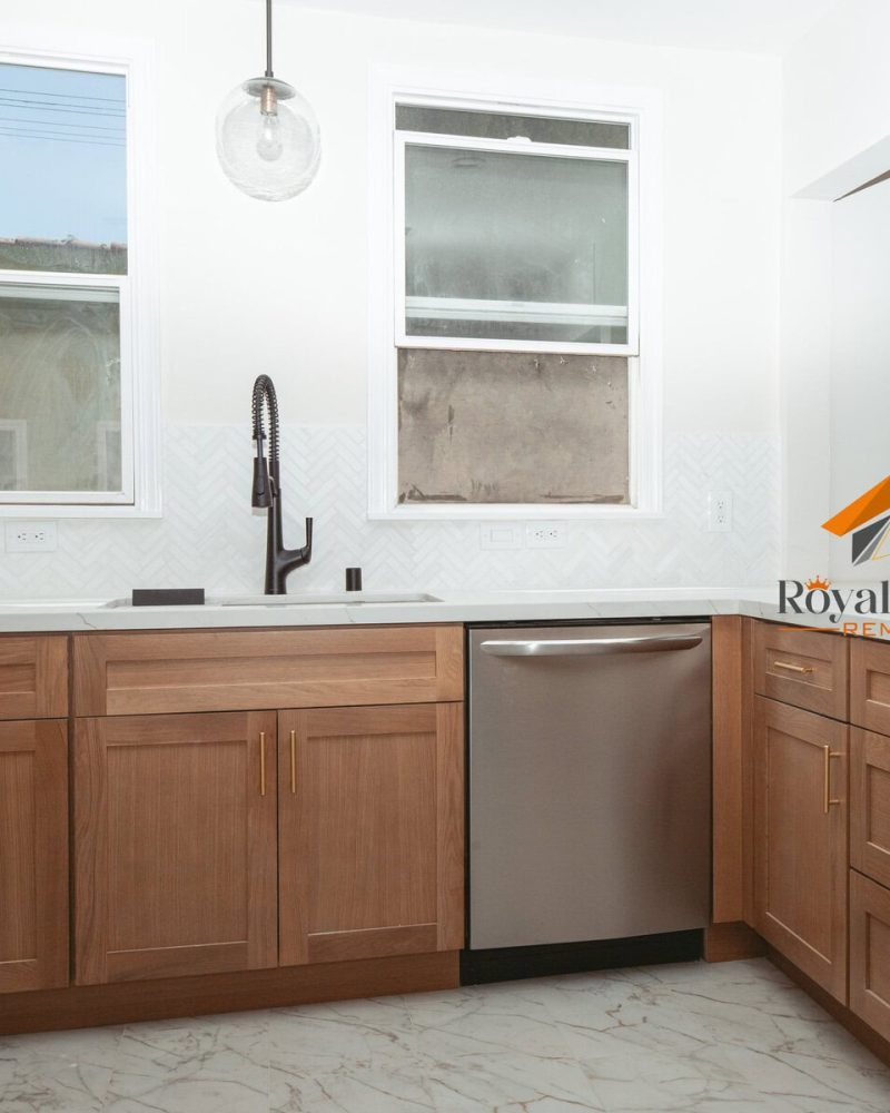 Modern kitchen with light wood cabinets, white countertops, and stainless steel appliances.