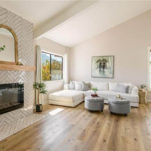 Living room with fireplace, white sectional sofa, and light wood flooring