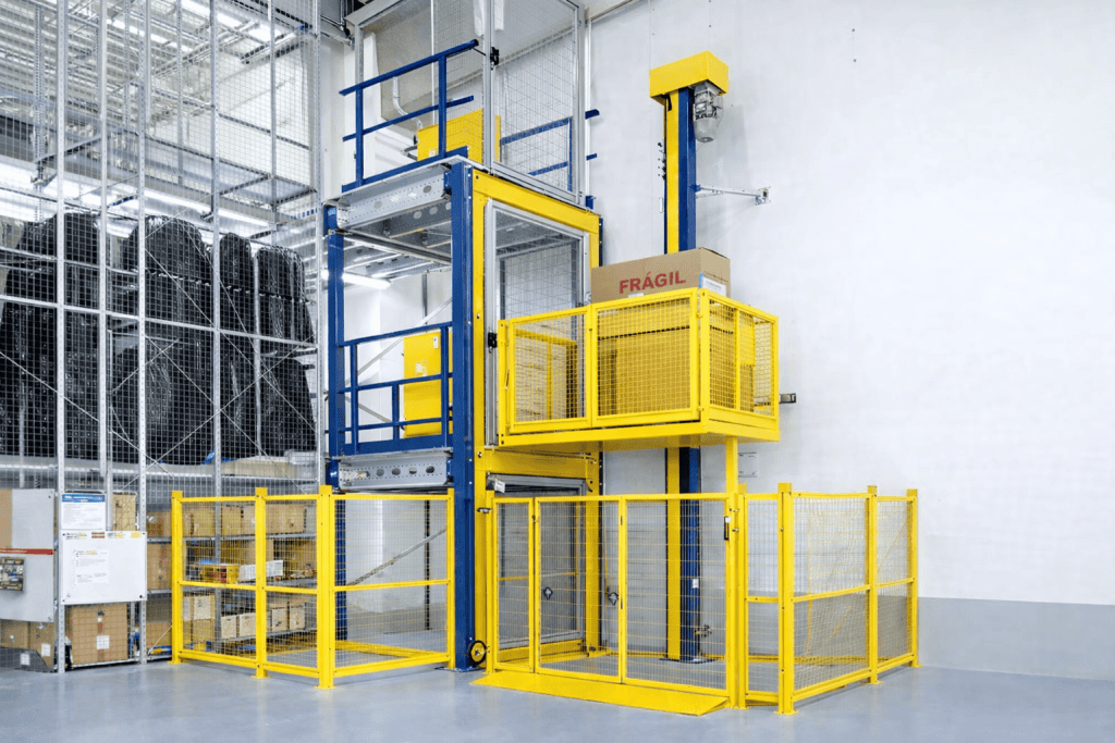 plataforma elevatória industrial para movimentação vertical de cargas com estrutura metálica e proteção NR12