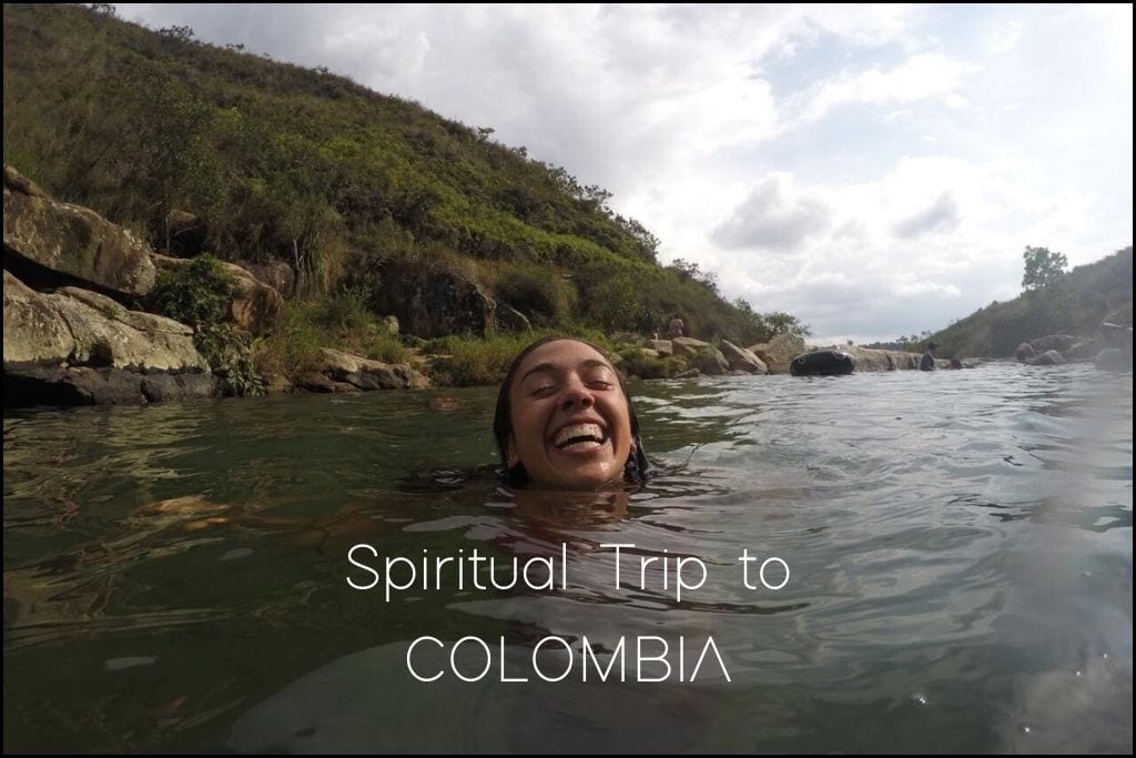 Find Your Spiritual Places in South America The joyous Giorgy individual floats in a clear river surrounded by rocky shores and lush vegetation, with the bright sky reflected in the water. 'Spiritual Trip to COLOMBIA' indicates a focus on the rejuvenating and spiritual experiences one can encounter in Colombia's natural settings.