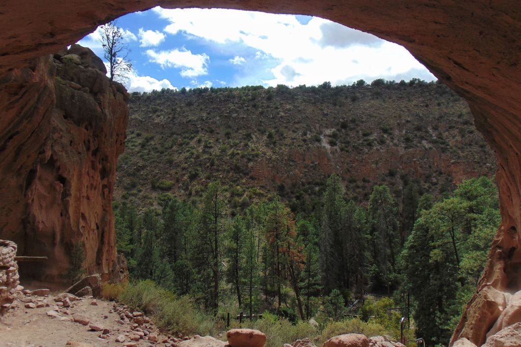 Your Guide to Santa Fe Spiritual Vortex in 2026 View from within a cave opening, framing a lush green forest and a mountain under a partly cloudy sky. The Santa Fe Spiritual Vortex.