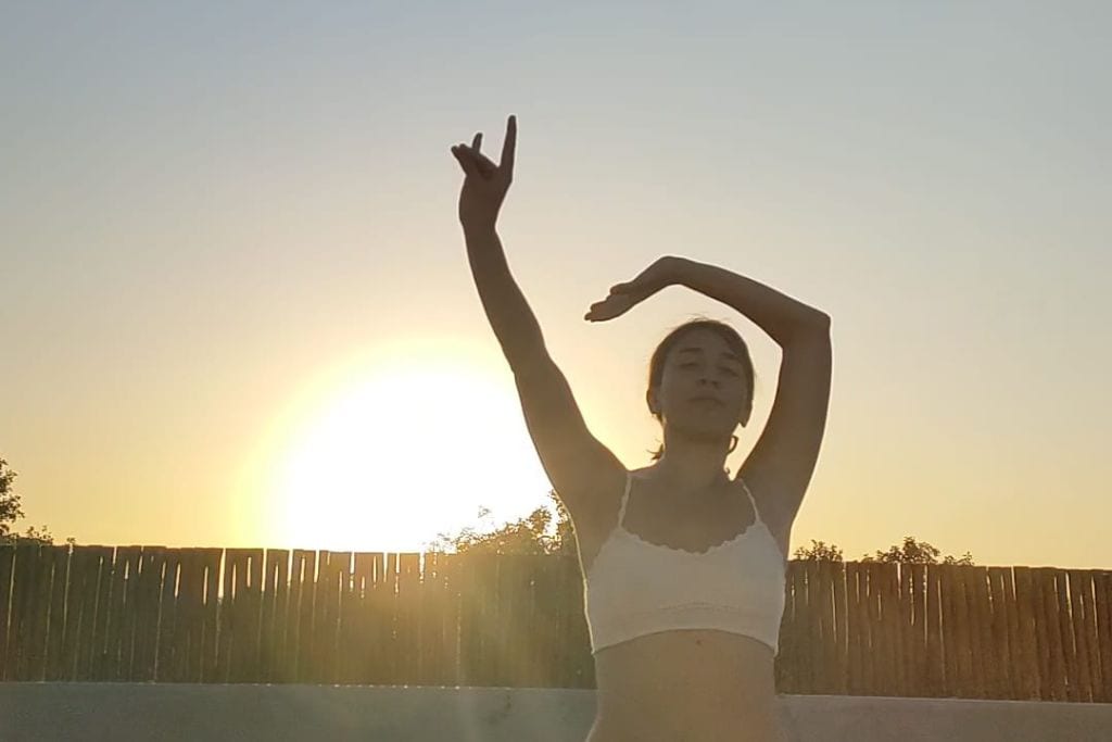 Your 2026 Spiritual Guide to The Pyramids of Teotihuacan Silhouette of a person performing a yoga pose against a golden sunset sky, with one arm extended upwards and fingers in a 'peace' sign, and the other arm curved gracefully above their head.