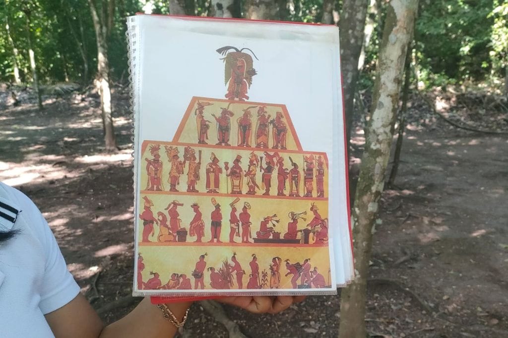 Your 2026 Spiritual Guide to The Pyramids of Teotihuacan Person holding up a book with a colorful illustration depicting scenes of ancient Teotihuacan life, providing visual insights into the question 'What Happened to Teotihuacan?' with depictions of figures in traditional attire engaging in various activities. Spiritual guid to the Pyramids oof Teotihucan.