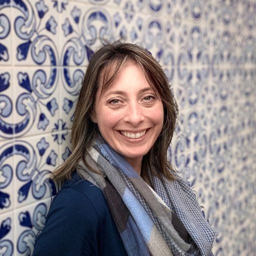 Discovering the Spiritual Essence of Haleakalā Volcano Hawaii Tracy Smyth author stands smiling in front of a decorative tiled wall, projecting a casual, approachable image.