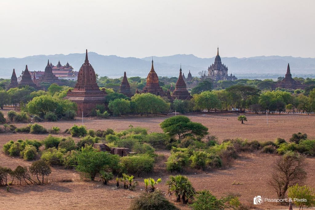 Is Bagan a Spiritual Place? Discover Why Should You Visit Bagan Myanmar in 2026! Aerial landscape of the ancient temples in Bagan, Myanmar, with several historic stupas scattered across the arid plains, backdropped by distant mountains.