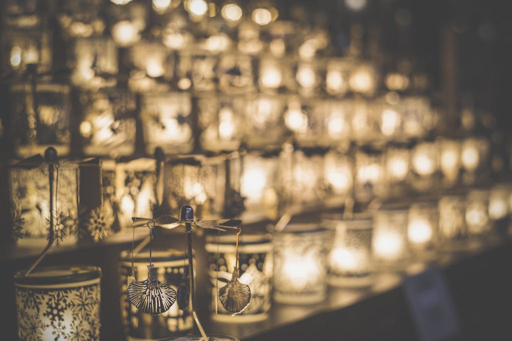 A clear glass candle holder sits elegantly on a brown wooden table. The candle holder is simple and transparent, showcasing its sleek design. The wooden table has a rich, warm tone, providing a natural and rustic contrast to the minimalist candle holder.