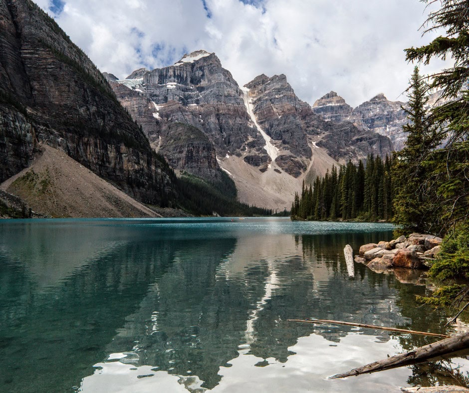 Is Banff Worth Visiting? Explore This Spiritual Place in 2026 A group of hikers walking across the vast, icy expanse of the Athabasca Glacier along the Icefields Parkway. The glacier is surrounded by steep, snow-covered mountains under a partly cloudy sky, highlighting the dramatic and rugged beauty of the area.