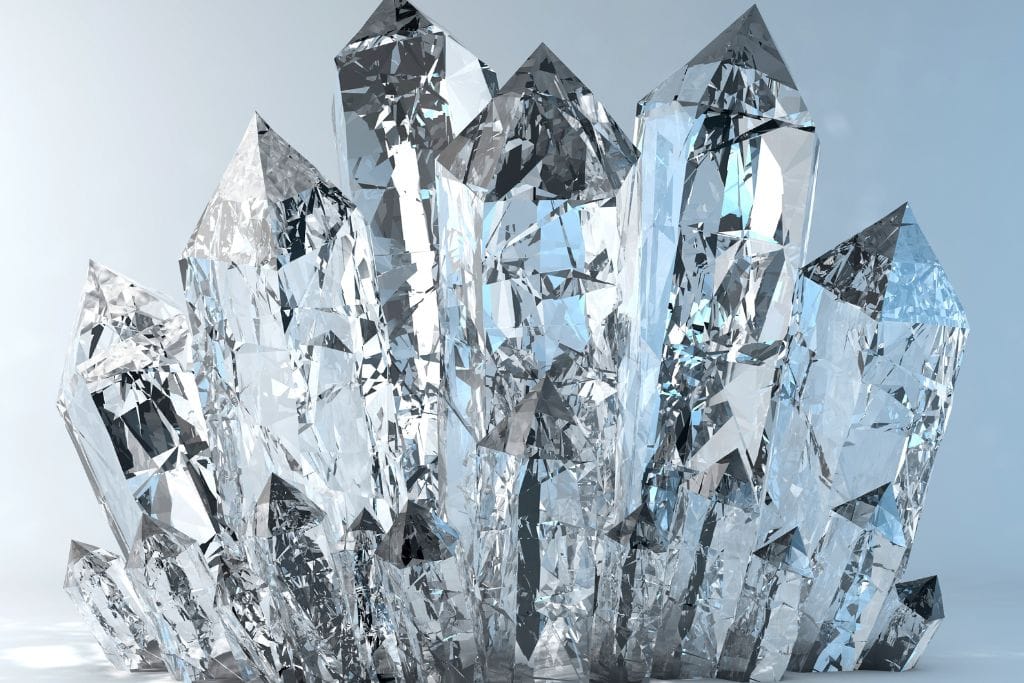 The image features a cluster of clear quartz crystals with sharp, faceted points. The crystals are transparent, reflecting and refracting light, creating a brilliant, sparkling effect. The background is a light, neutral tone that highlights the clarity and geometric structure of the quartz.