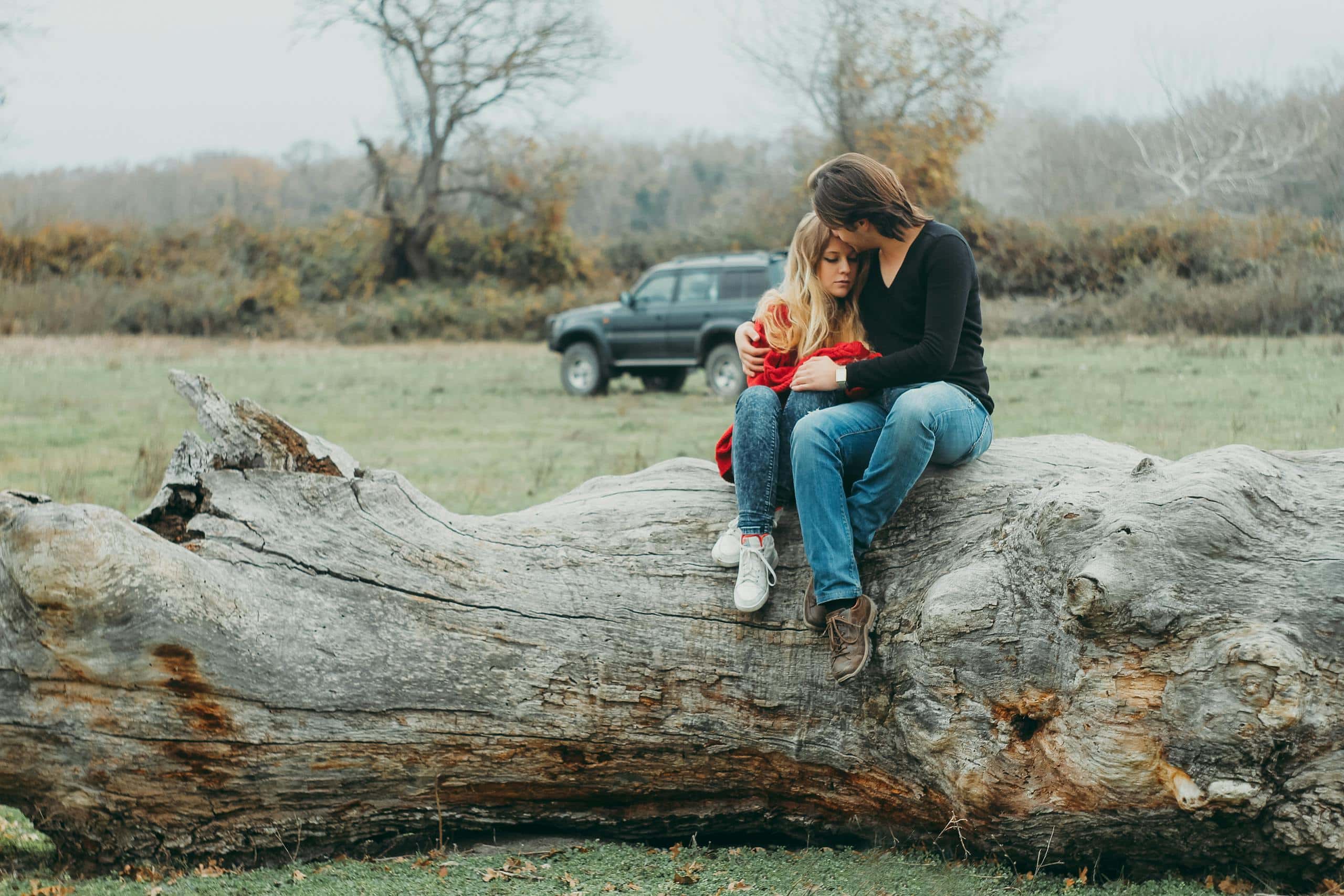 The Hidden Meaning Behind Angel Number 1044 Close-up image of a mother and daughter sitting together on a tree log in a natural setting. The mother has her arm around the daughter, and both are gazing out at the surrounding landscape, which includes trees and greenery. The sunlight gently filters through the leaves, creating a peaceful and serene atmosphere. The daughter leans in close, showing the bond and affection they share. The image conveys warmth, love, and the beauty of a quiet moment in nature representing Angel Number 1044 Love Meaning.