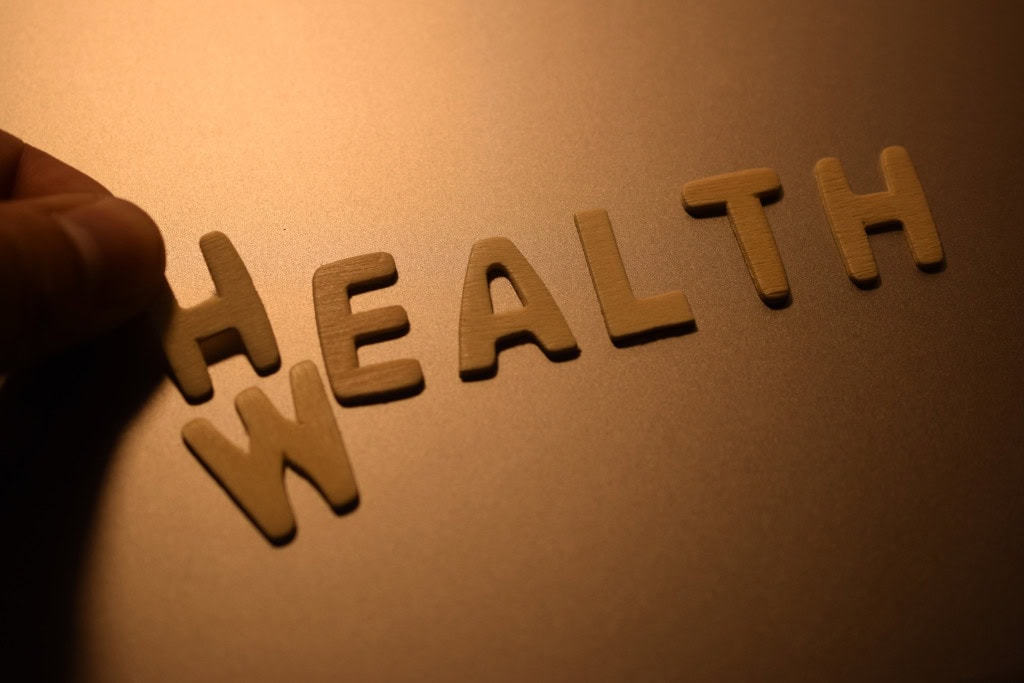 Cleansing Your House from Negative Energy: Everything You Need to Know! This image shows wooden letters arranged to form the word "HEALTH," with the letter "W" placed at the beginning to temporarily spell "WEALTH." A hand is seen adjusting the letters, emphasizing the connection between health and wealth. The warm lighting highlights the letters, suggesting an intentional focus on balance or priorities in life.