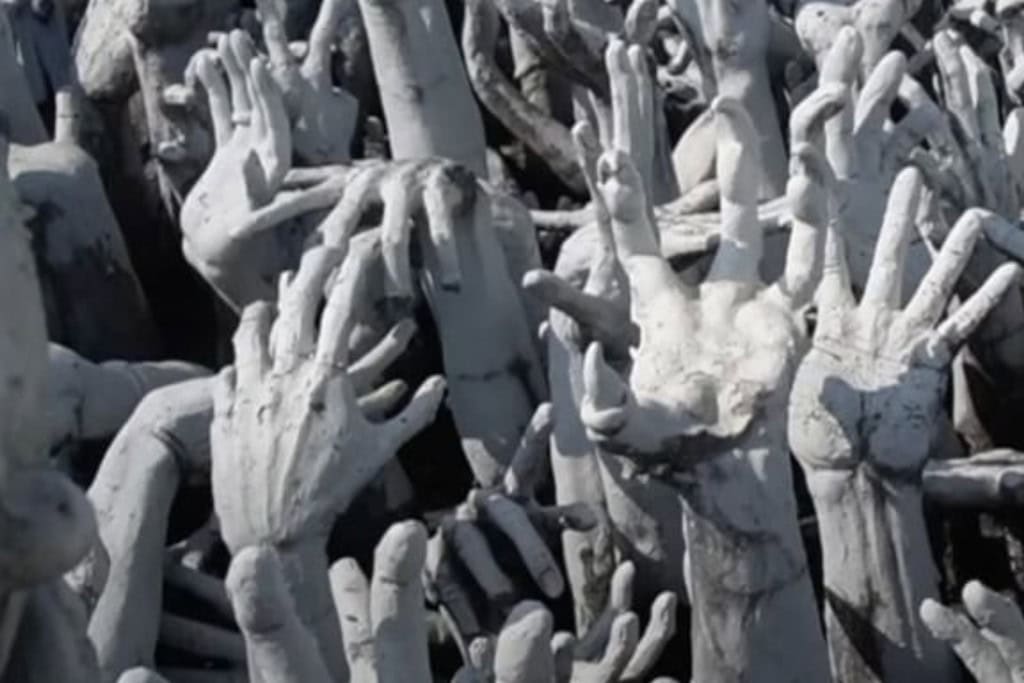 Wat Rong Khun: The White Temple Of Chiang Rai, Thailand This image shows a striking and symbolic sculpture from Wat Rong Khun (the White Temple) in Chiang Rai, Thailand, depicting numerous white hands reaching upwards. These hands, often interpreted as souls in suffering or reaching out for salvation, are part of the temple's symbolic journey through desire and the cycle of life. The details and positioning of the hands create a haunting and dramatic effect.