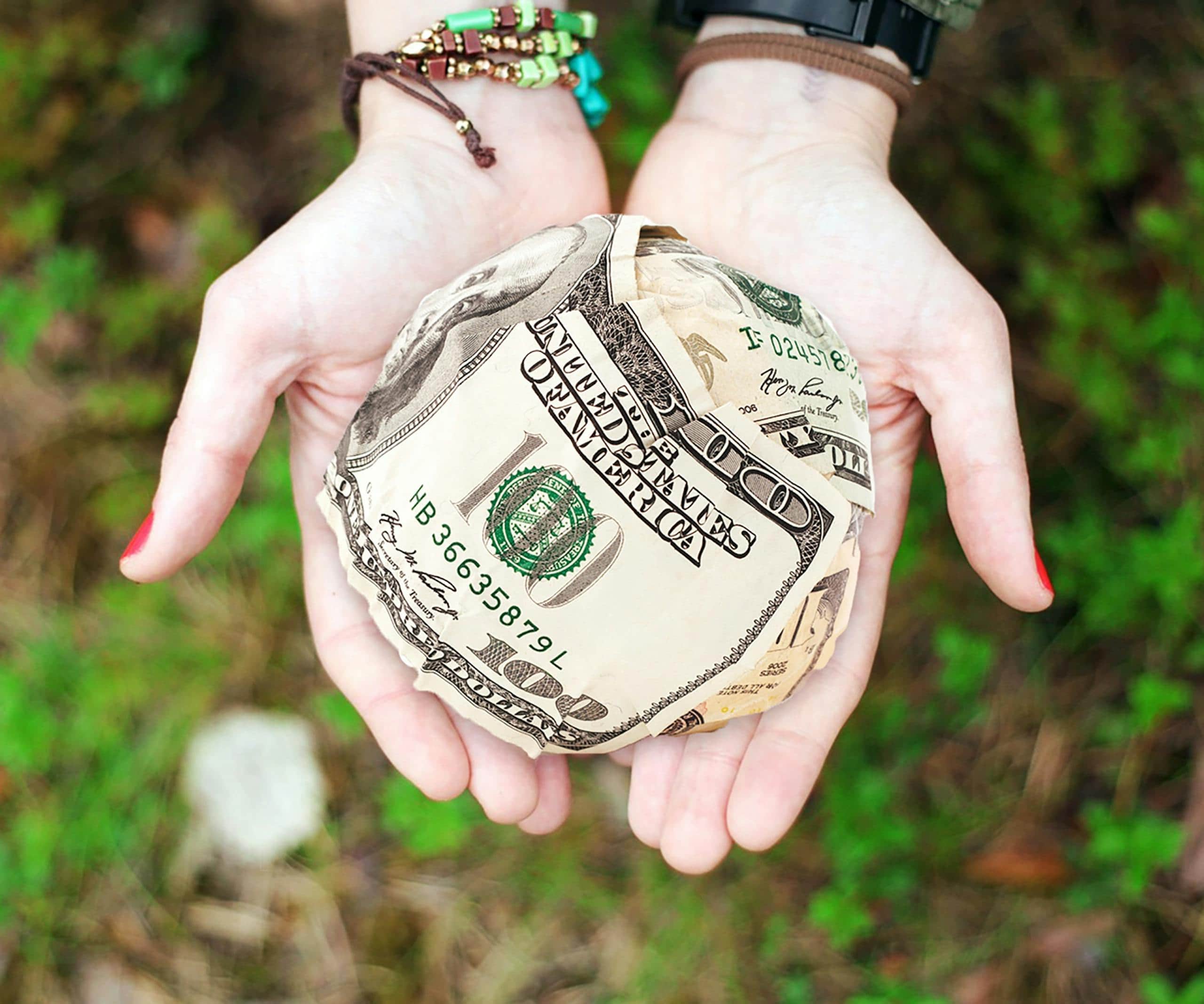 Angel Number 0000: Spiritual Messages & Symbolic Meaning Image of hands holding crumpled money outdoors, with the background featuring blurred greenery and natural light. The crumpled bills are clasped tightly, emphasizing a sense of urgency or desperation. The natural outdoor setting contrasts with the condition of the money, creating a thought-provoking scene.