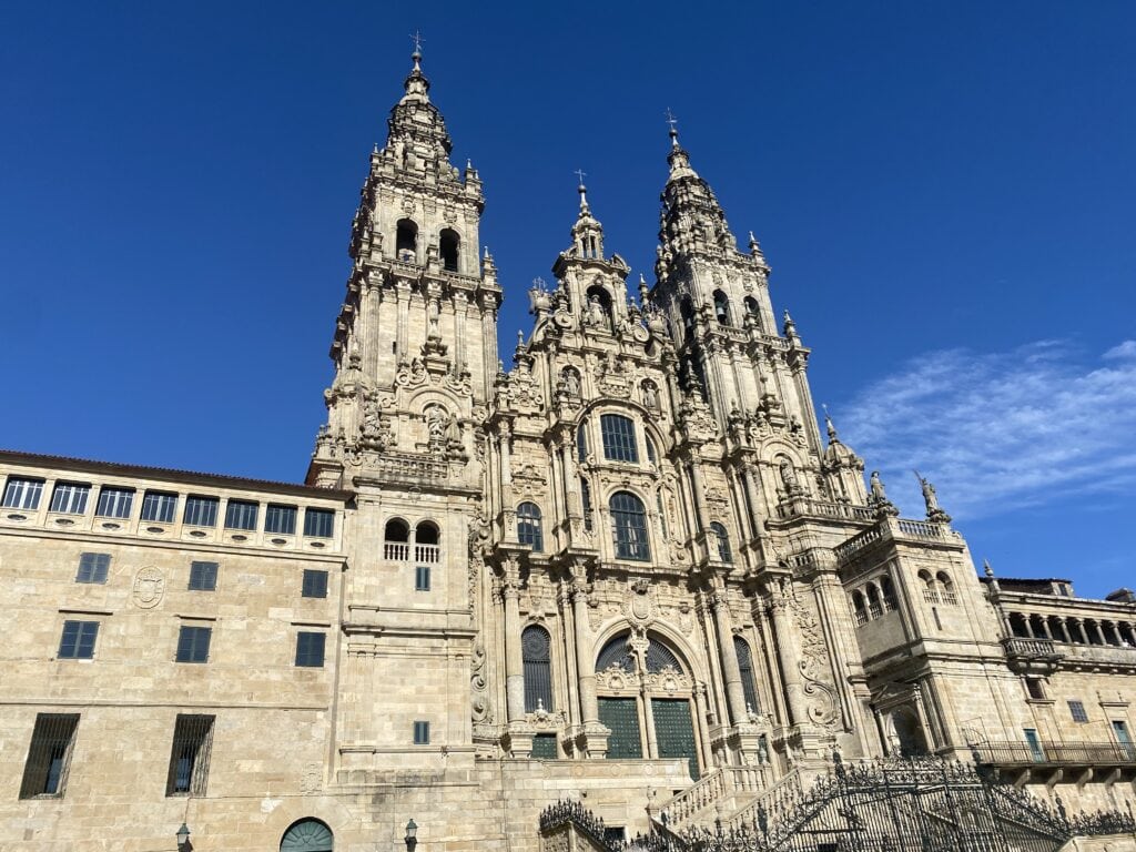 What is the spiritual meaning of Santiago de Compostela? The iconic facade of the Cathedral of Santiago de Compostela under a bright blue sky, showcasing its intricate baroque architecture and historical significance as the final destination of the Camino de Santiago pilgrimage.