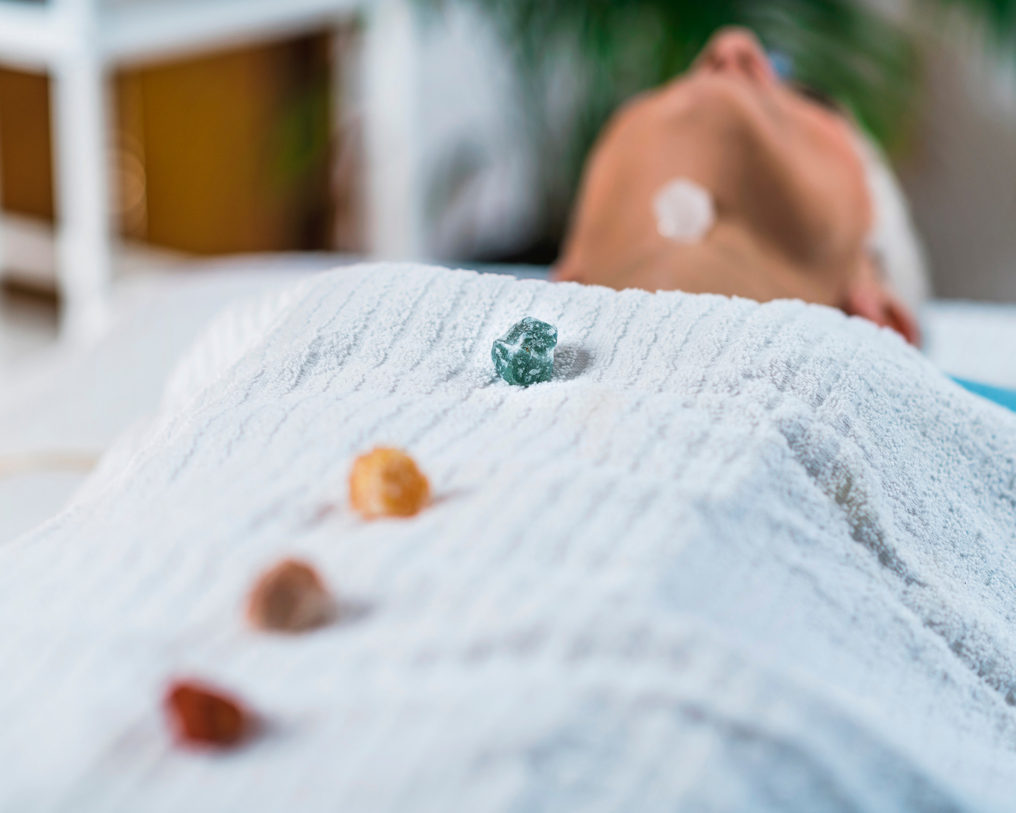 Person lying down with healing crystals placed along the body during a chakra balancing session.
