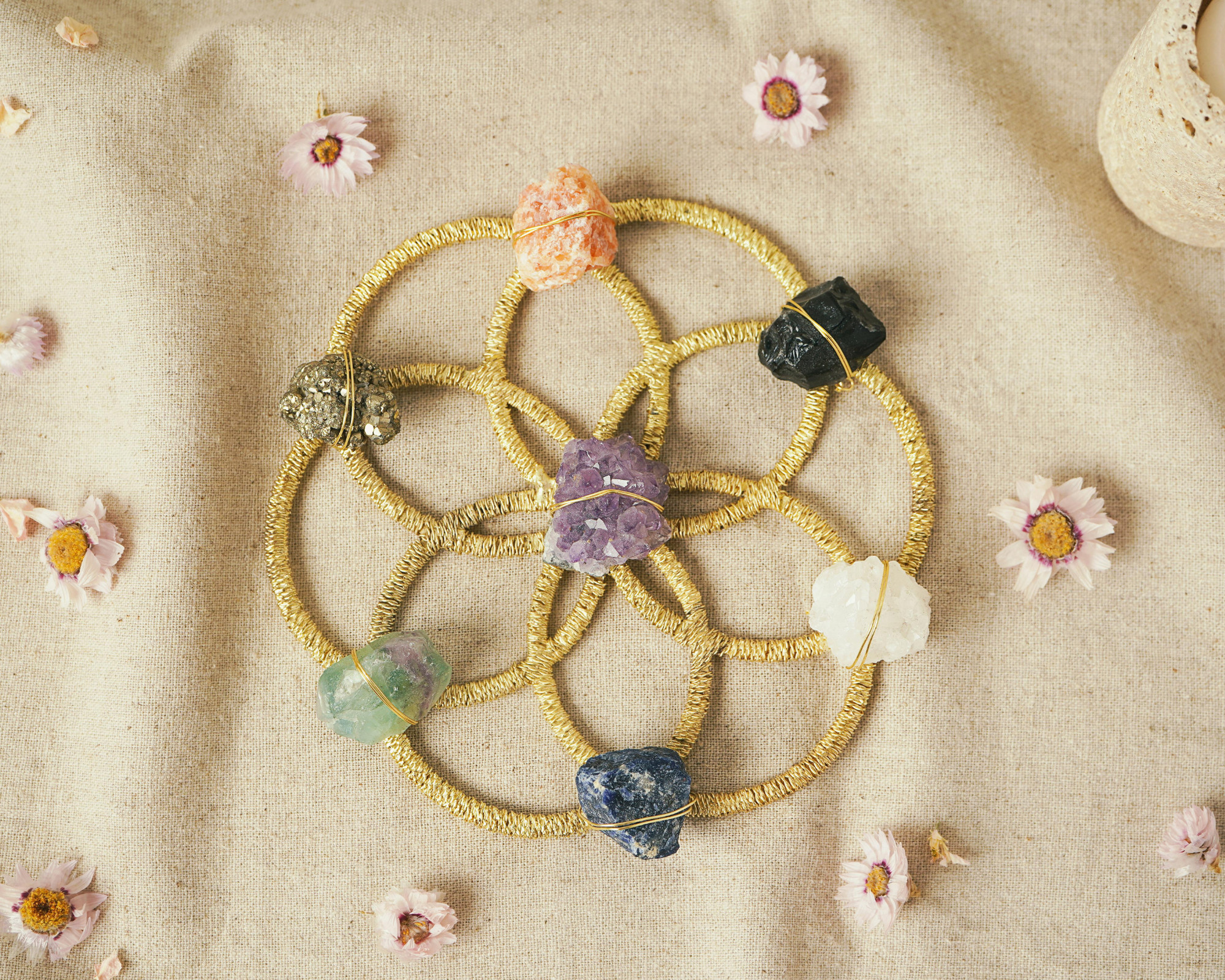 Crystal grid with various healing stones arranged on a beige cloth, representing the 8 chakras and energy balancing practices.