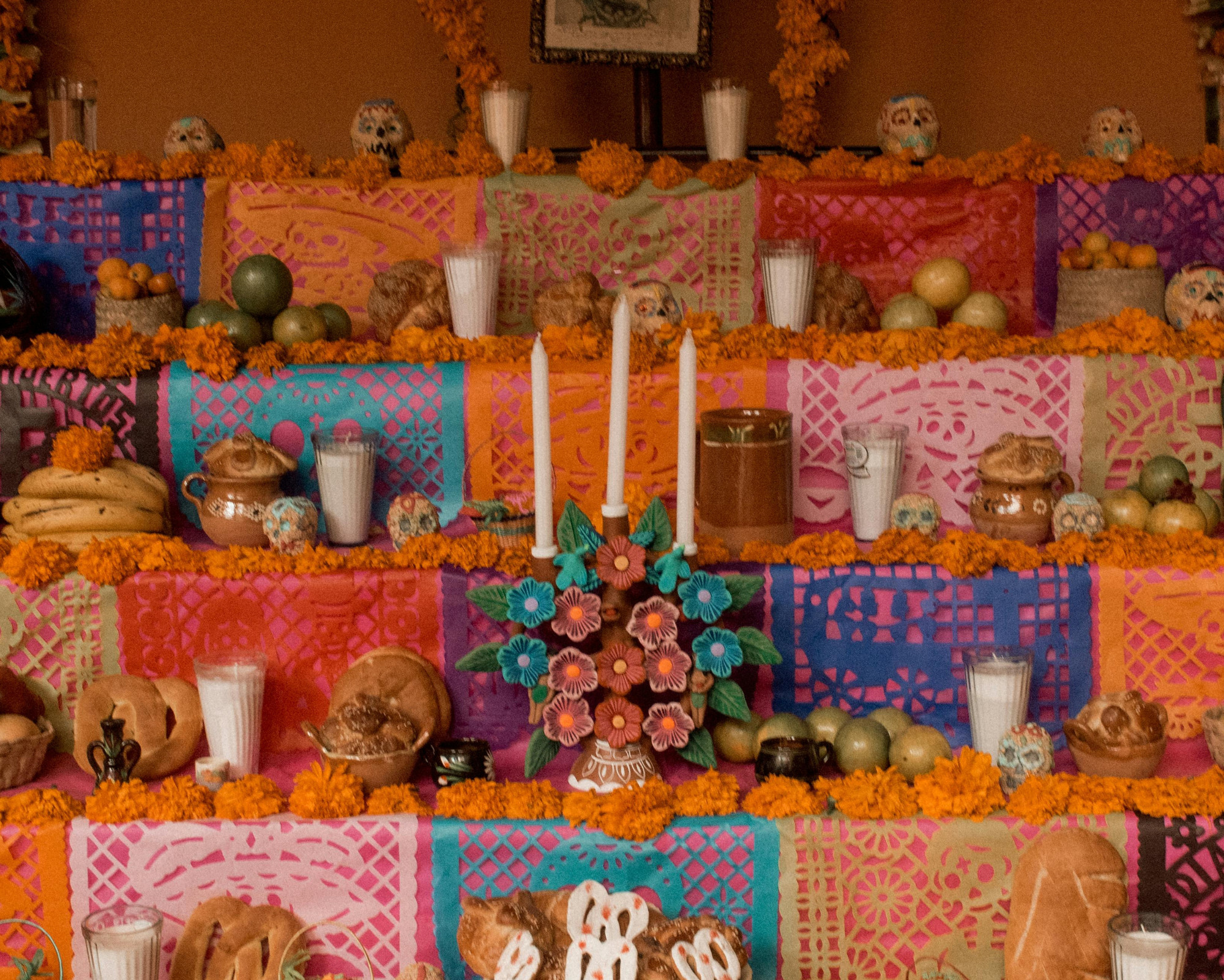 A vibrant ancestor altar decorated with candles, fruit, and offerings, representing what to do for Samhain to honor loved ones who have passed.