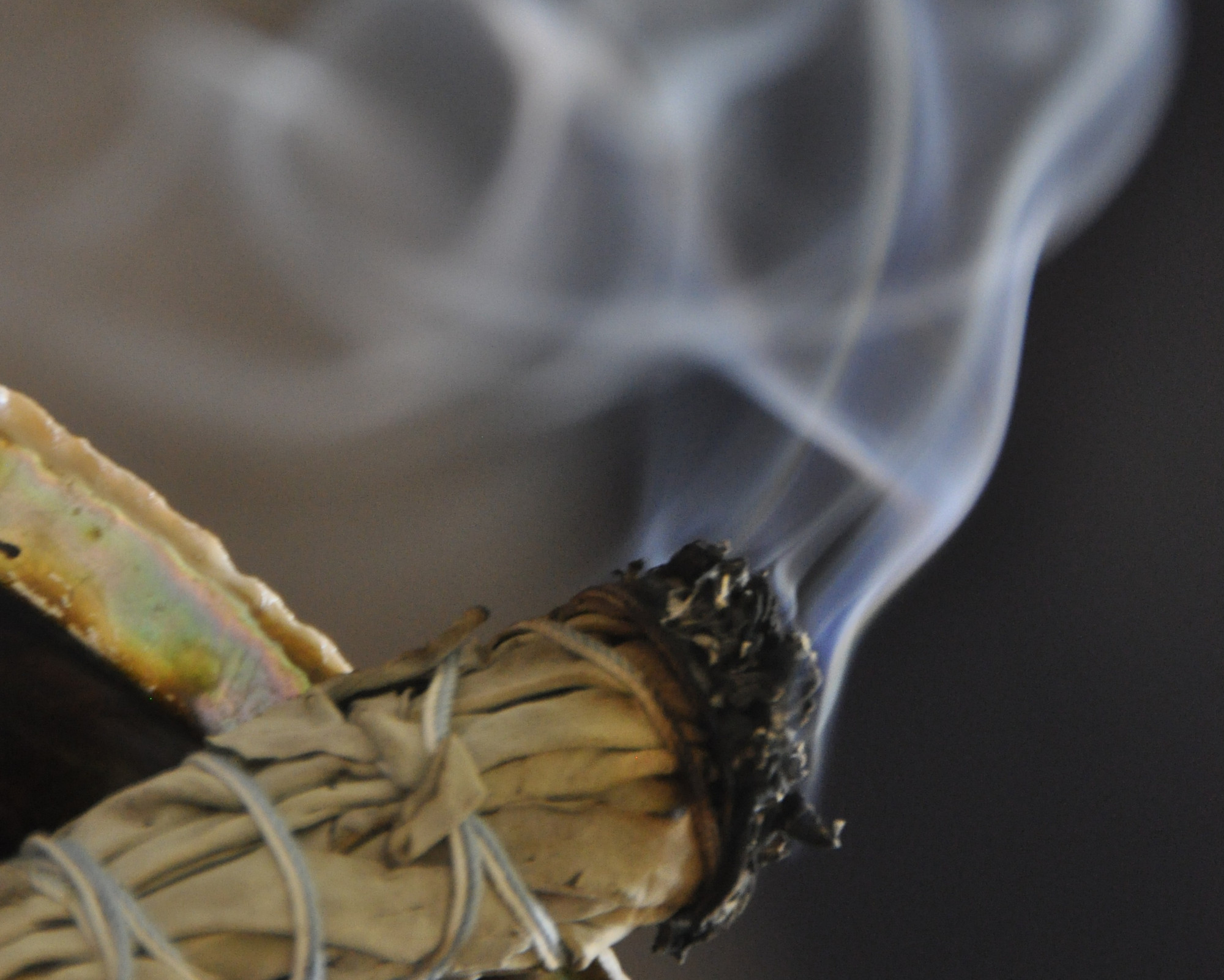 A smudge stick burning and releasing cleansing smoke, showing what to do for Samhain when preparing your home for spiritual purification.
