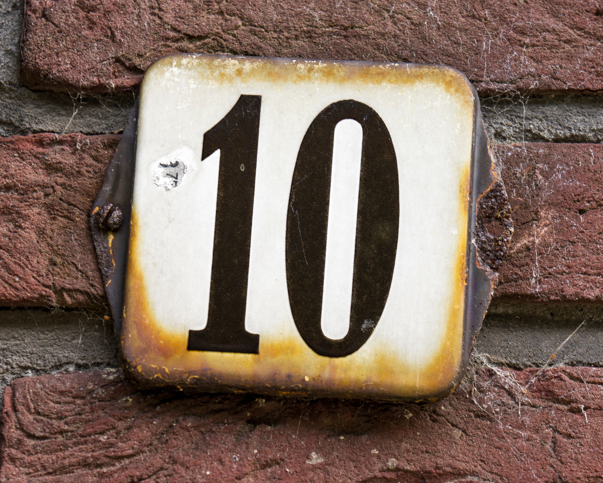 Angel Number 1010 Old metal house number sign with the number 10, often linked to people noticing repeating patterns connected to the 1010 angel number.