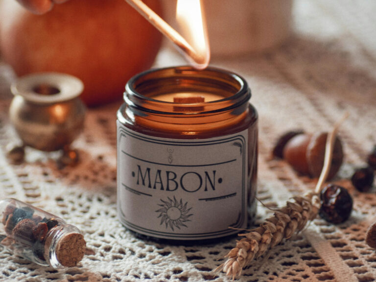 Mabon candle burning beside wheat and acorns, ritual setup for Celebrating Mabon and preparing for the darker half of the year.