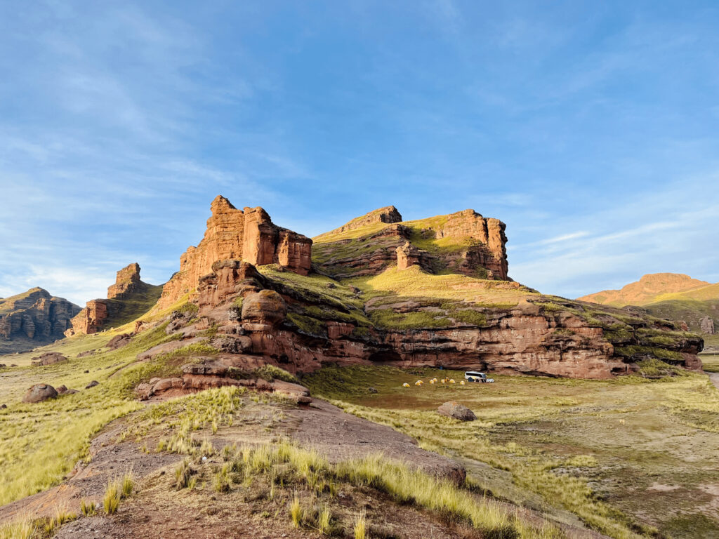 When the Mountains Called Me Home: How Peru Re-Mapped My Inner Compass Sunrise lighting the dramatic rock formations and campsite tents at Tinajani Canyon in the Peruvian Andes.