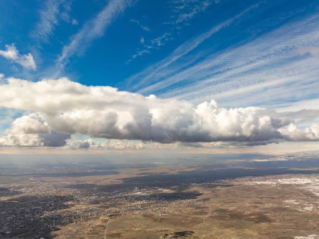 Sky and clouds over a vast landscape with a clear horizon.