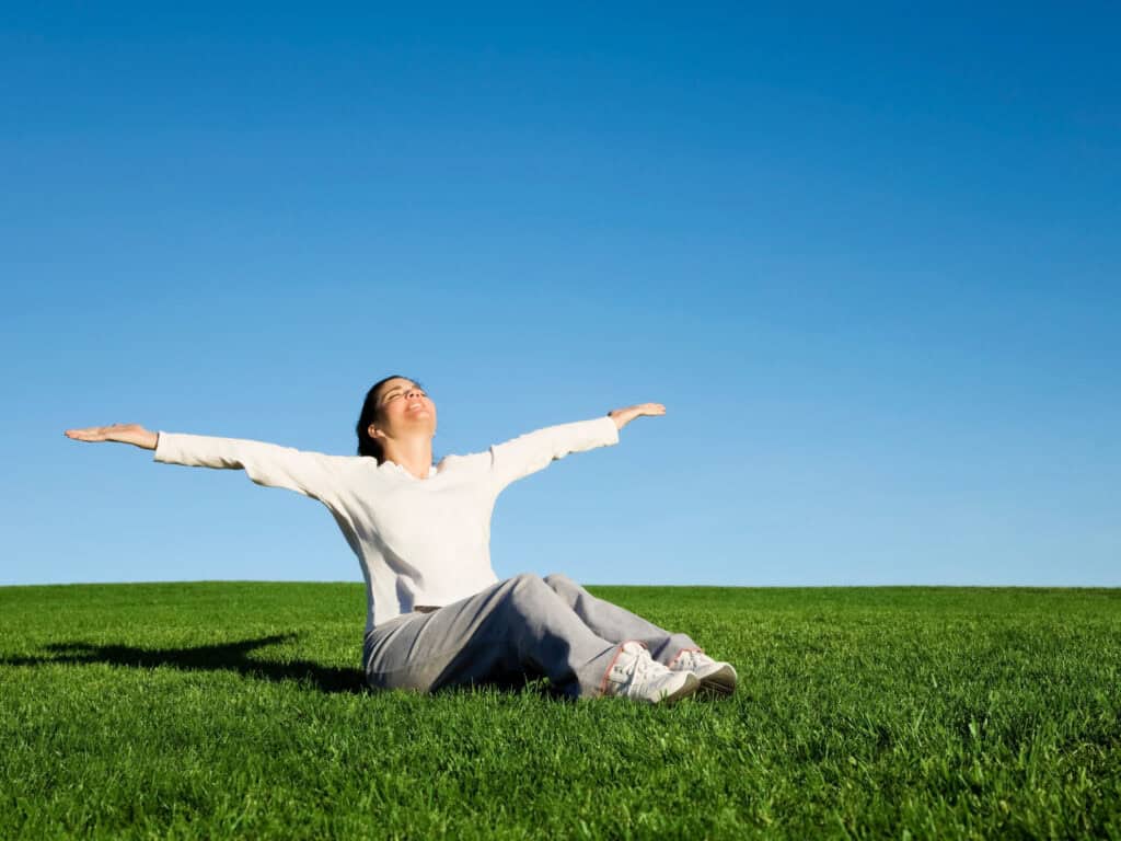Woman practicing yoga outdoors under clear blue sky.