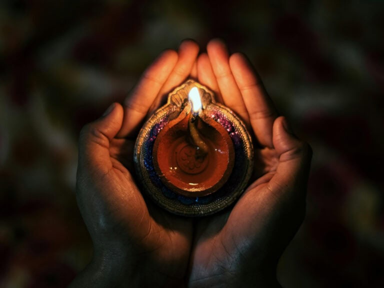 Hands holding a lit candle representing the fire element and spiritual transformation.