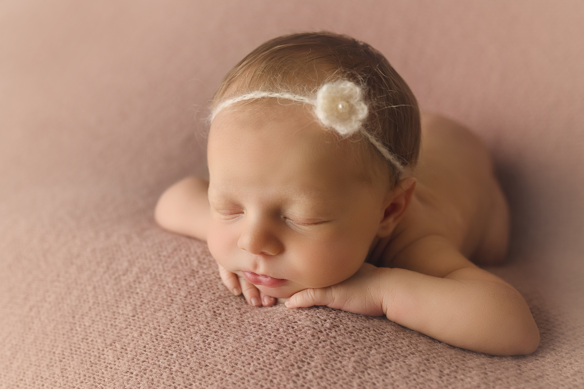newborn baby girl resting face on hands