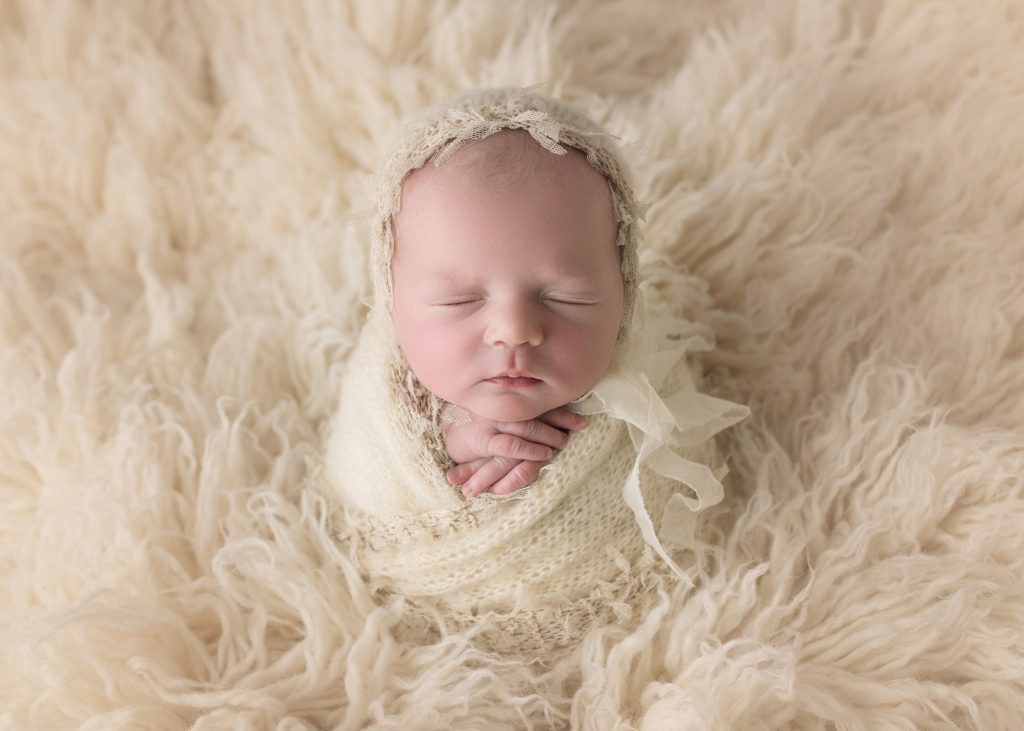 newborn baby girl in white fur and matching bonnet and wrap