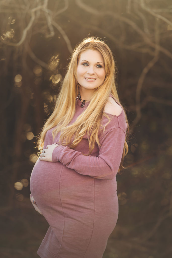 Pregnant Mama wearing red dress near tree