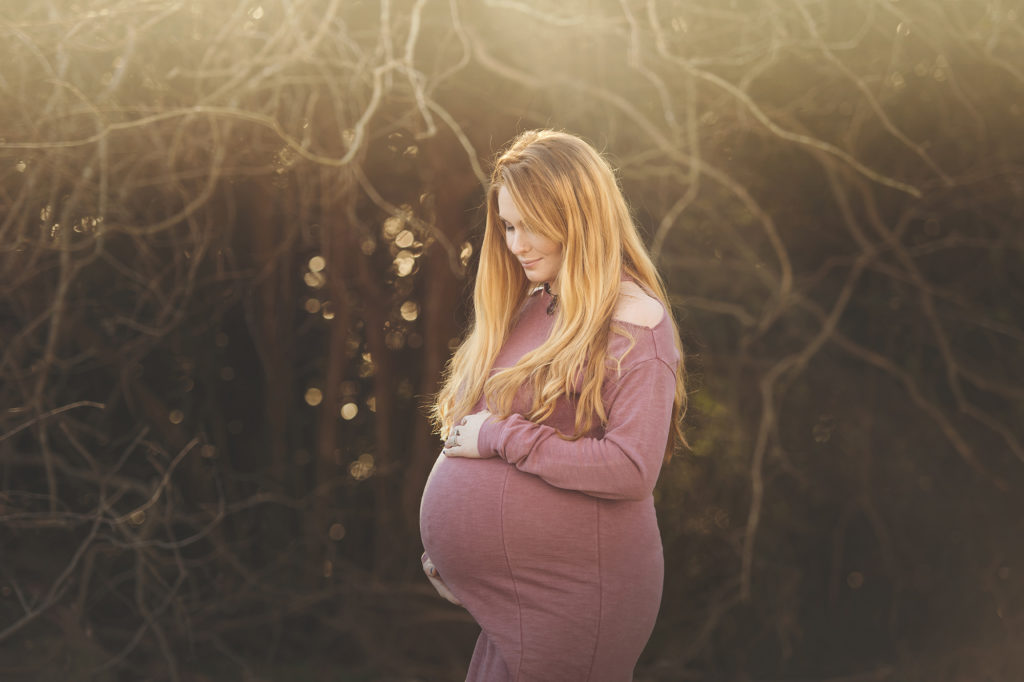 Pregnant Mama wearing red dress near tree